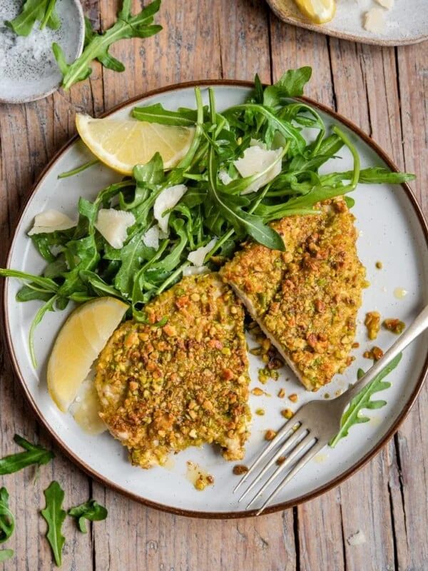 Pistachio chicken on a plate with arugula and parmesan