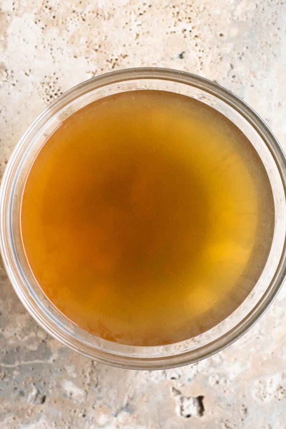 An overhead shot of Italian broth 'brodo di carne' in a glass bowl.