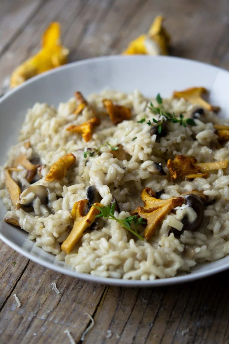 A side shot of creamy mushroom risotto in a white marble bowl