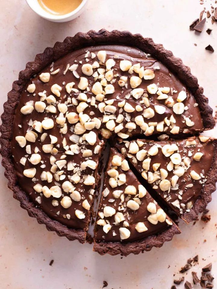 An overhead shot of a chocolate tart topped with hazelnuts