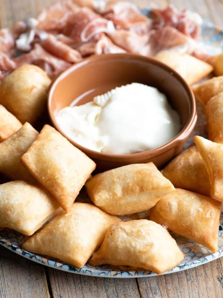 Gnocco Fritto (Italian fried dough) on a plate with cheese and prosciutto.