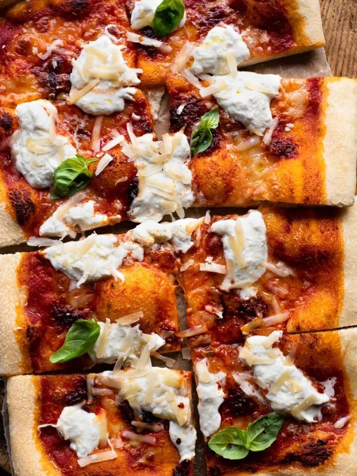 An overhead shot of a large Nduja pizza with burrata cheese and basil cut into 8 slices.