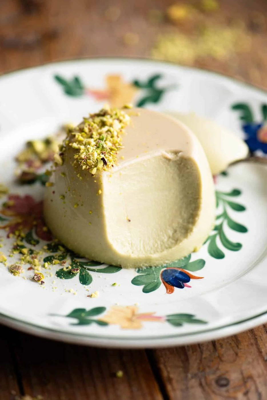 A close up of a pistachio panna cotta with a bite out to show the creamy inside.