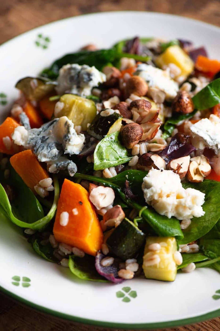 A close up of a farro salad on a plate with butternut squash, spinach and gorgonzoal.