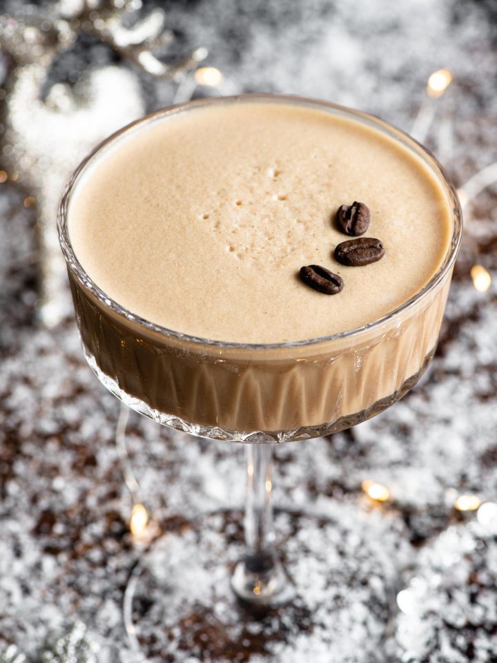 A close up of a martini macchiato in a snowy theme with fairy lights