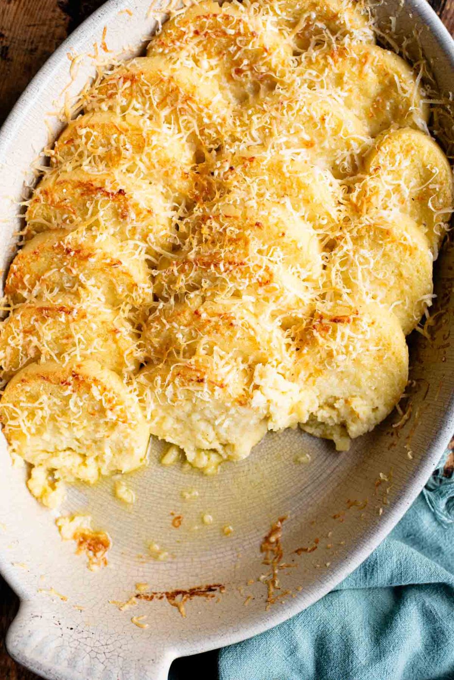 A close up of Gnocchi alla Romana in a baking dish with some removed showing the buttery dish.
