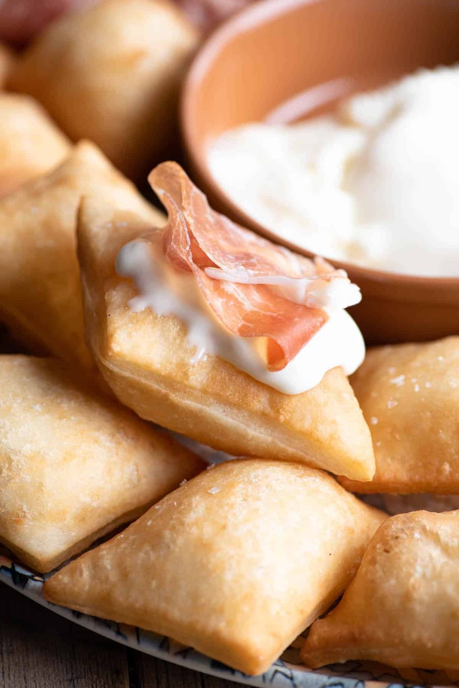 A close up of Gnocco Fritto, Italian Fried Dough with cheese and prosciutto on top.