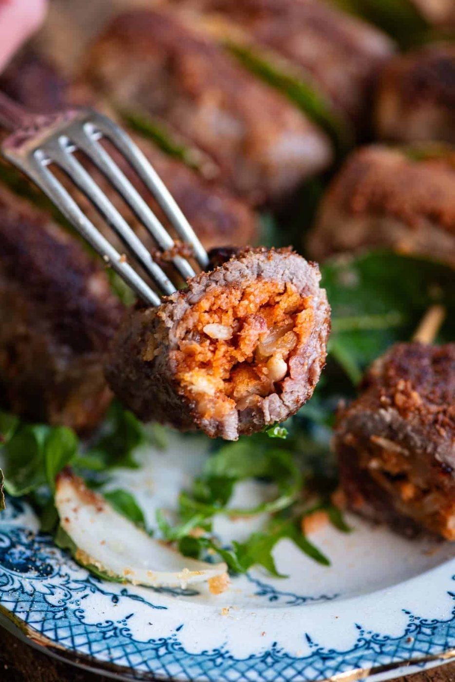 A close up of one Sicilian stuffed beef roll cut in half on a fork.
