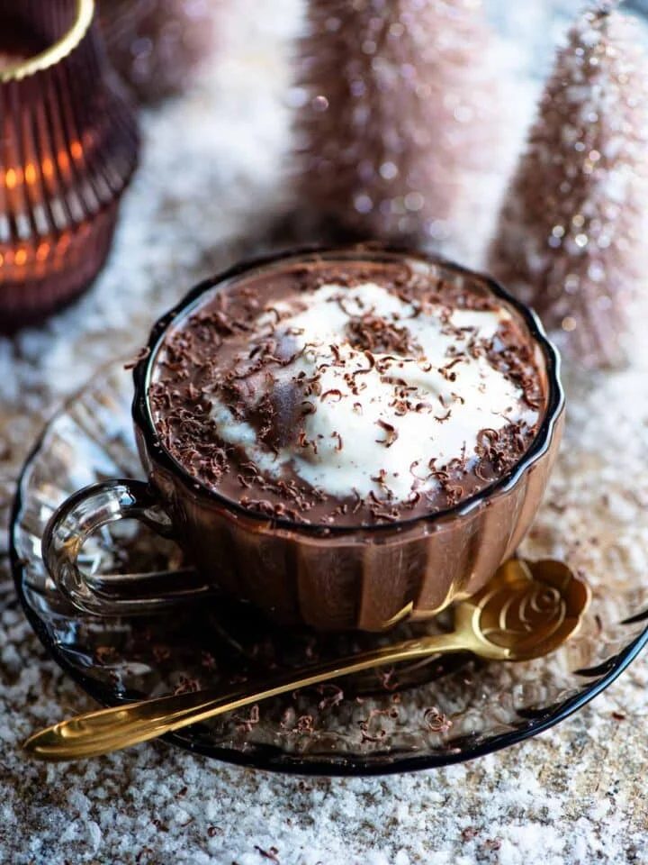 Hot chocolate in a glass mug with ice cream on top and fake snow around.