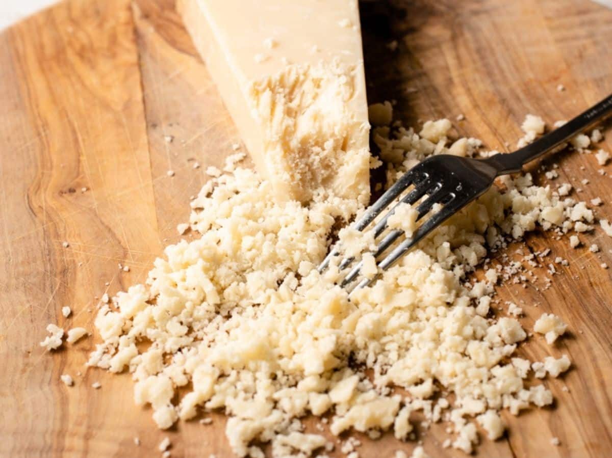 A close up of Parmigiano Reggiano being crumbled with a fork.