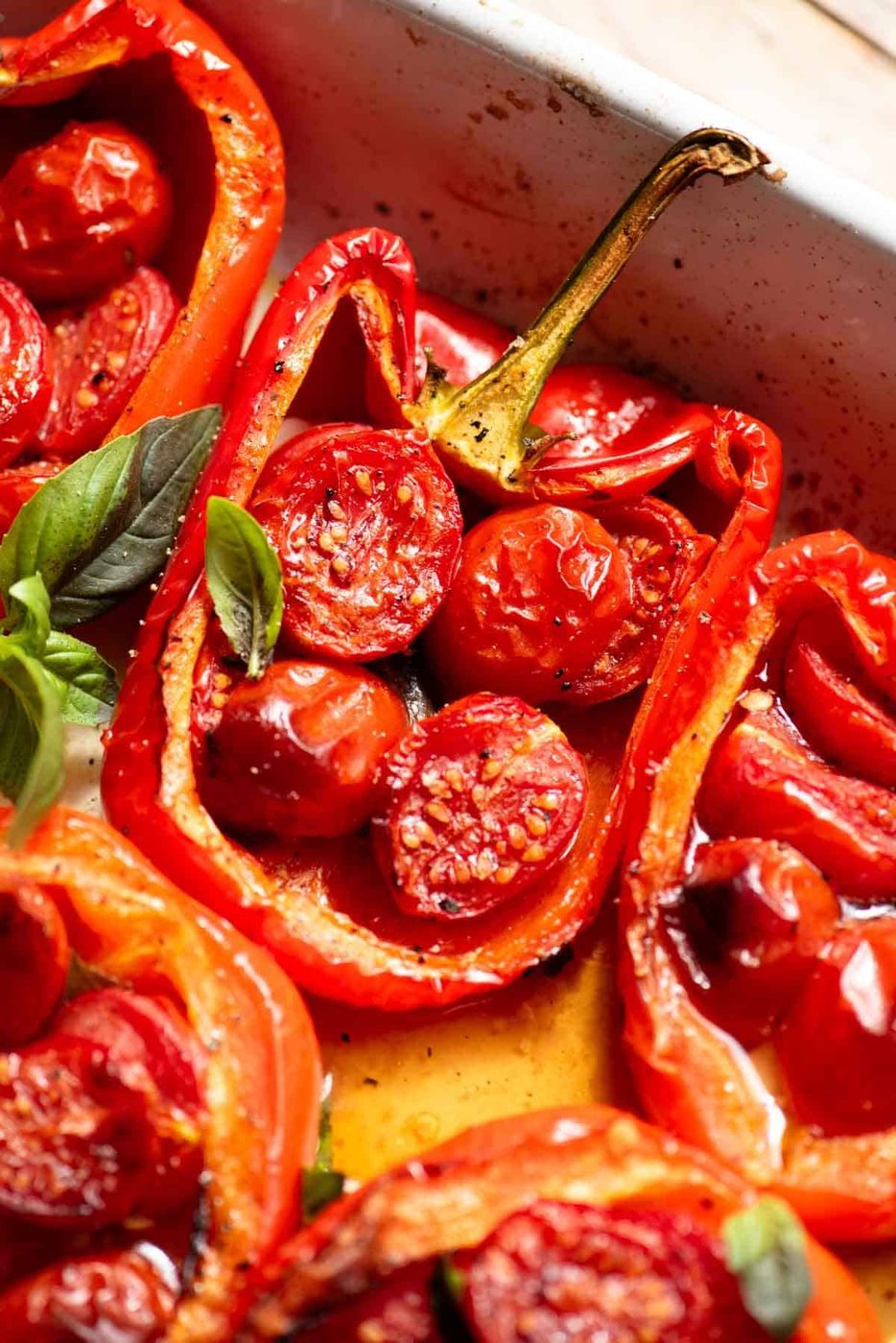 A close up of a red bell pepper stuffed with cherry tomatoes, basil, garlic and anchovies.