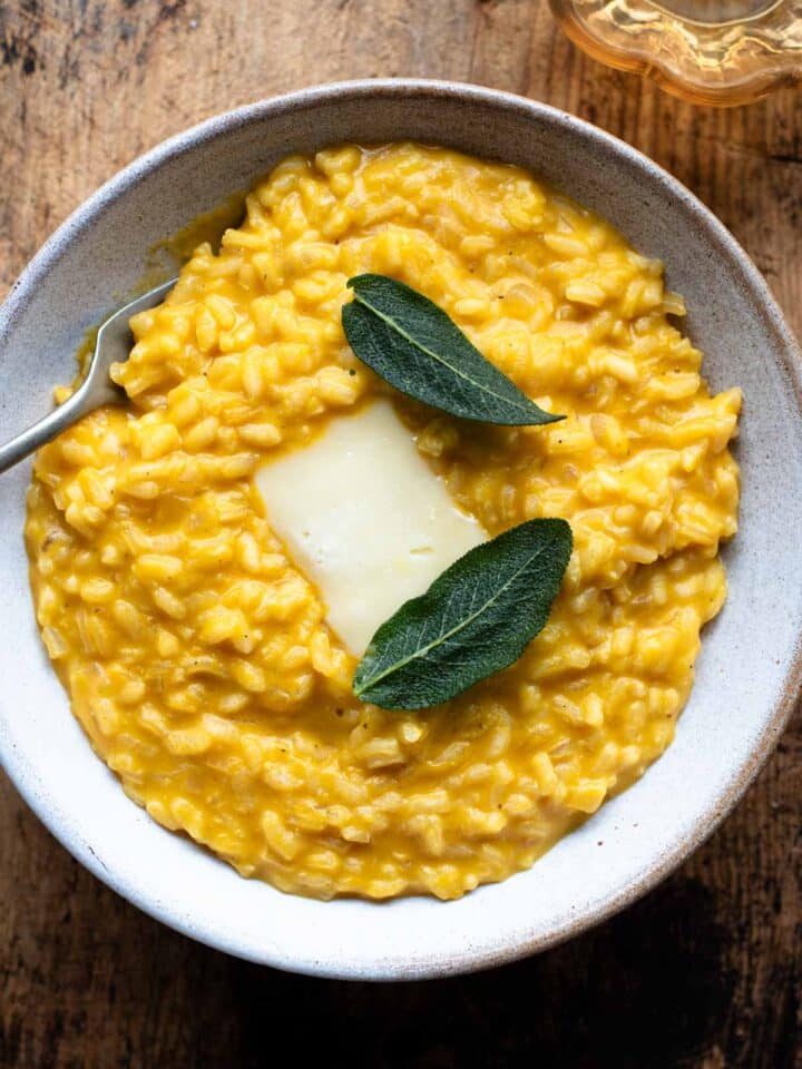 An overhead shot of a Pumpkin Risotto with a slice of Taleggio cheese and crispy sage on top.