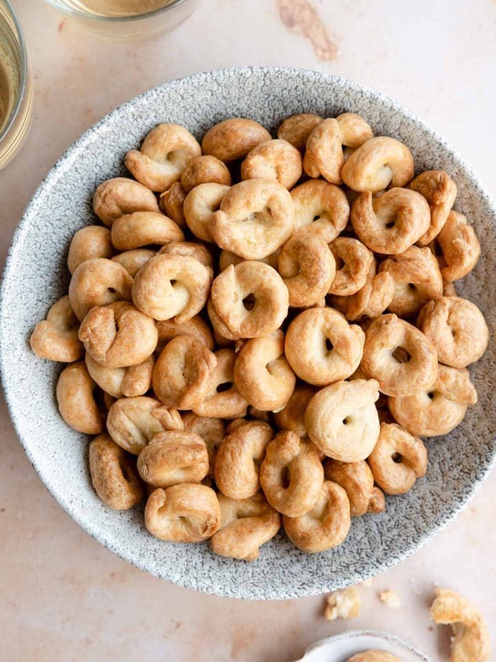 An overhead shot of Taralli in a bowl with glasses of wine at the side