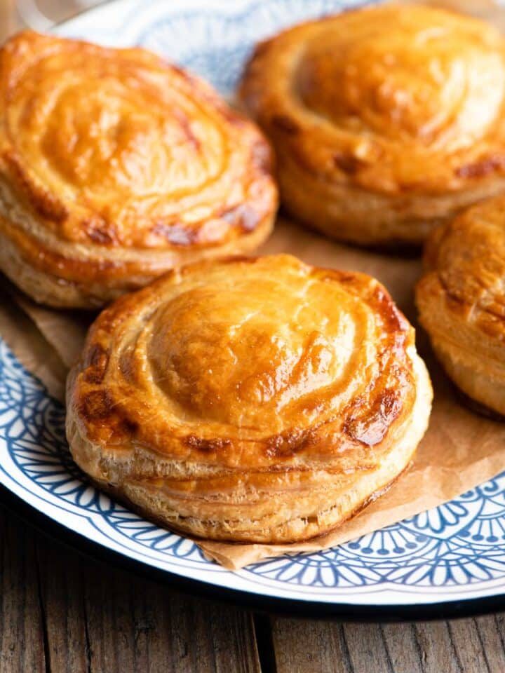 Four Rustici Leccesi (Italian pastries) on a blue plate.