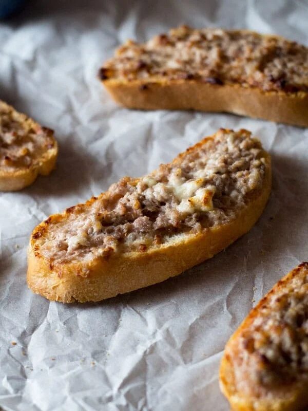 This two ingredient stracchino and sausage crostini is so simple and crazy delicious. Tangy, soft cheese is mixed with Italian sausage and spread on some thick crusty bread. An easy sausage crostini recipe you're sure to love. More authentic italian recipes at