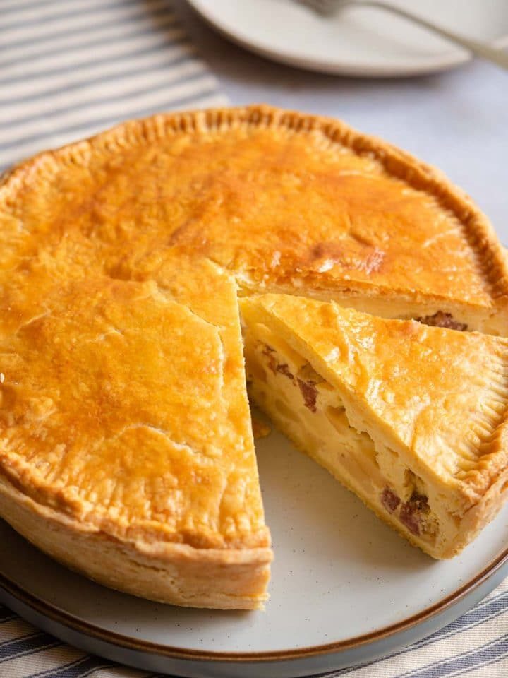 Pizza Rustica on a serving plate with a slice cut