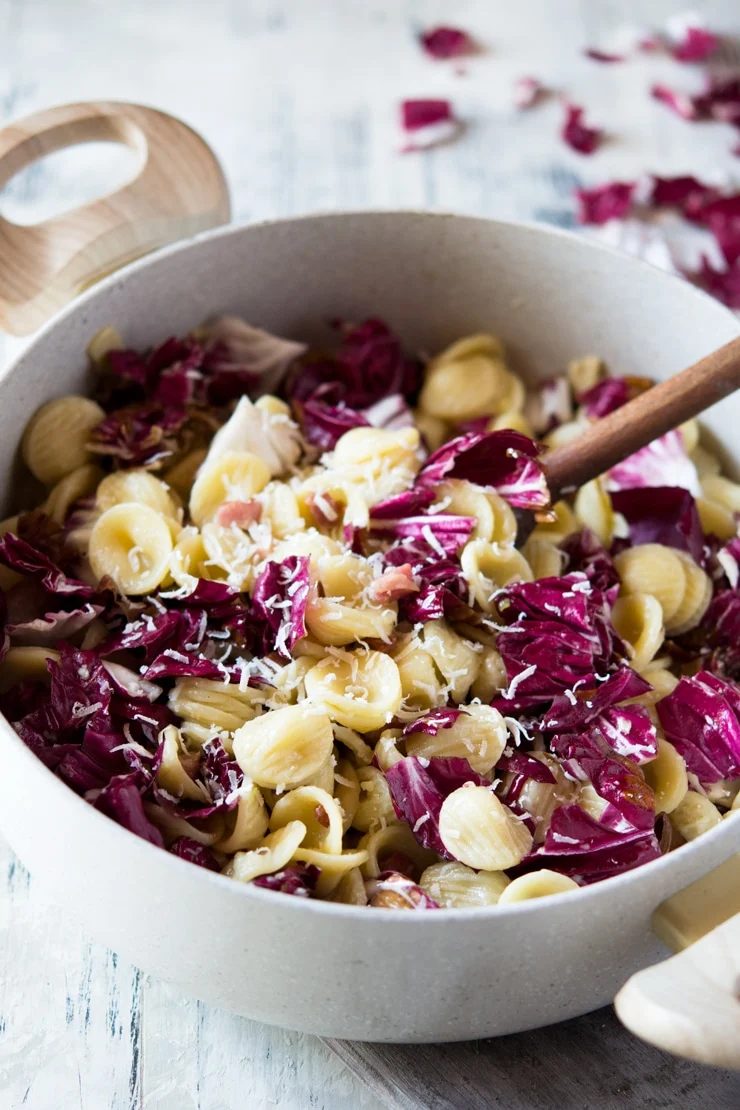A close up of Orecchiette Pasta and Pancetta And Radicchio with a wooden spoon in a large pan