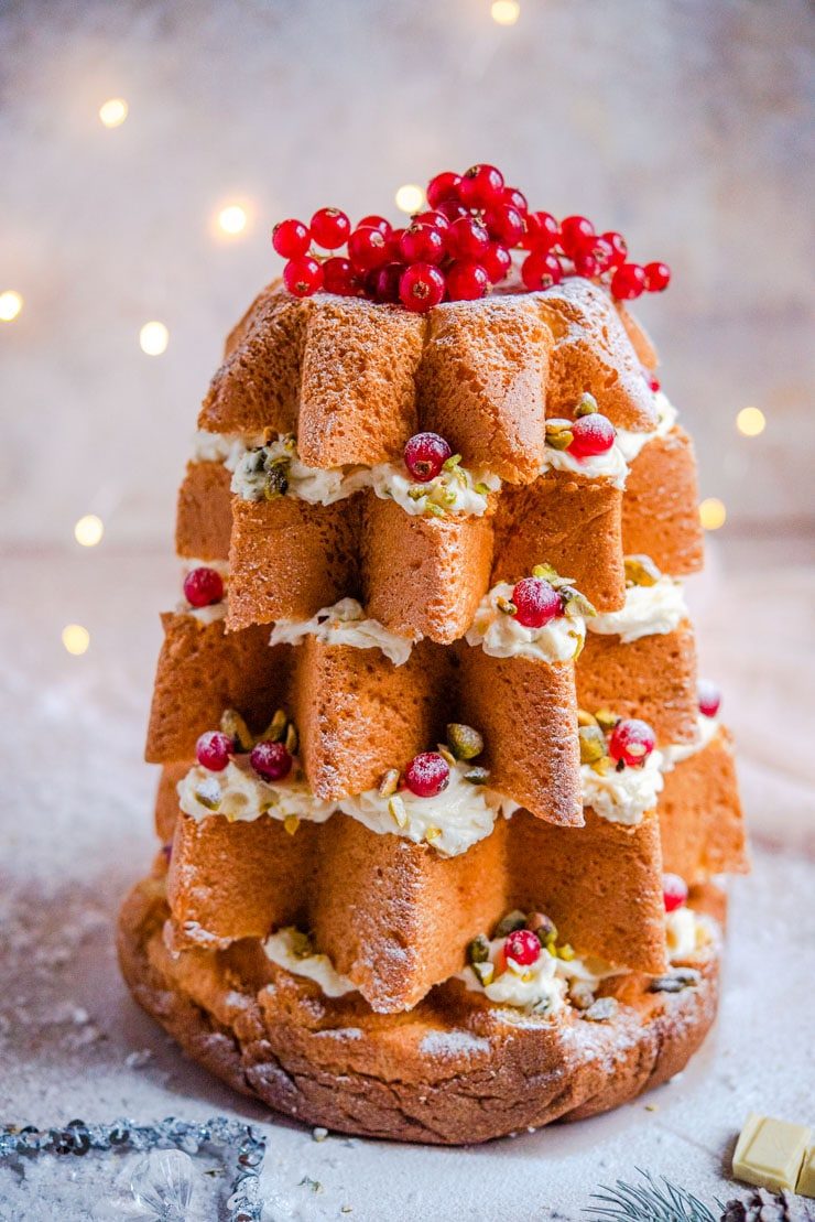 A close up of a pandoro christmas tree cake with fairy lights in the background