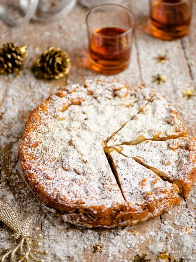 Panforte on a wooden table cut into slices with christmas decorations around