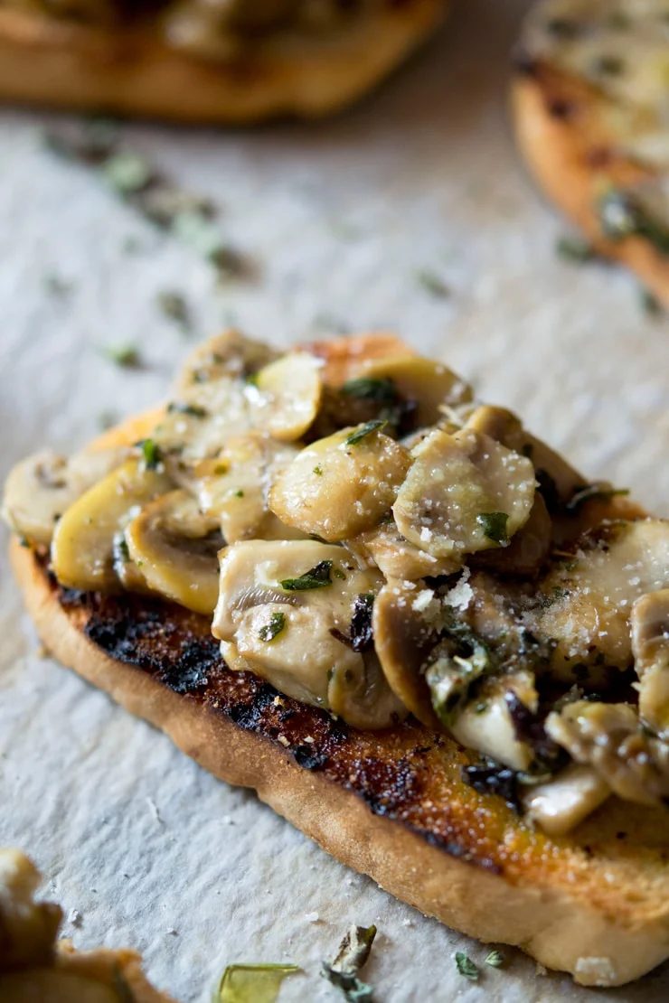 A close up of mushroom toasts with oregano and parmesan