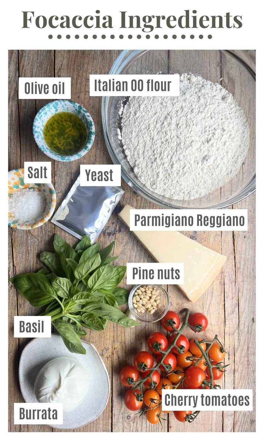 Ingredients laid out on a rustic wooden surface to make a focaccia with cherry tomatoes, basil pesto and burrata.