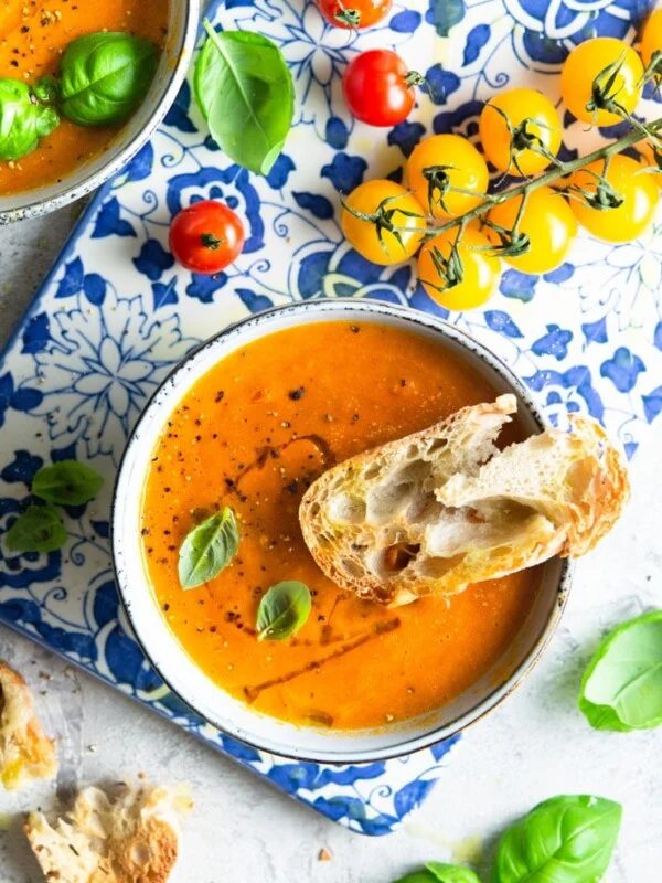 An overhead shot of roasted tomato soup with crusty bread a the side