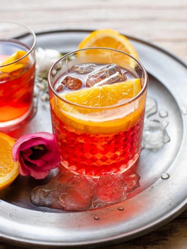 A Negroni cocktail in a glass with a slice of orange