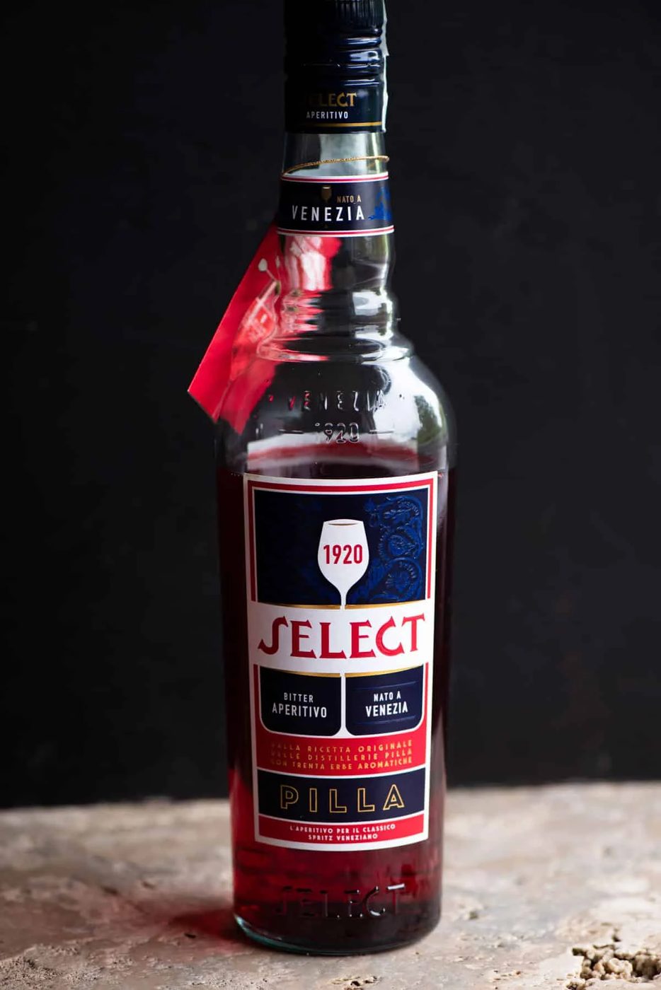 A bottle of Select Aperitivo on a stone work surface with a black background.
