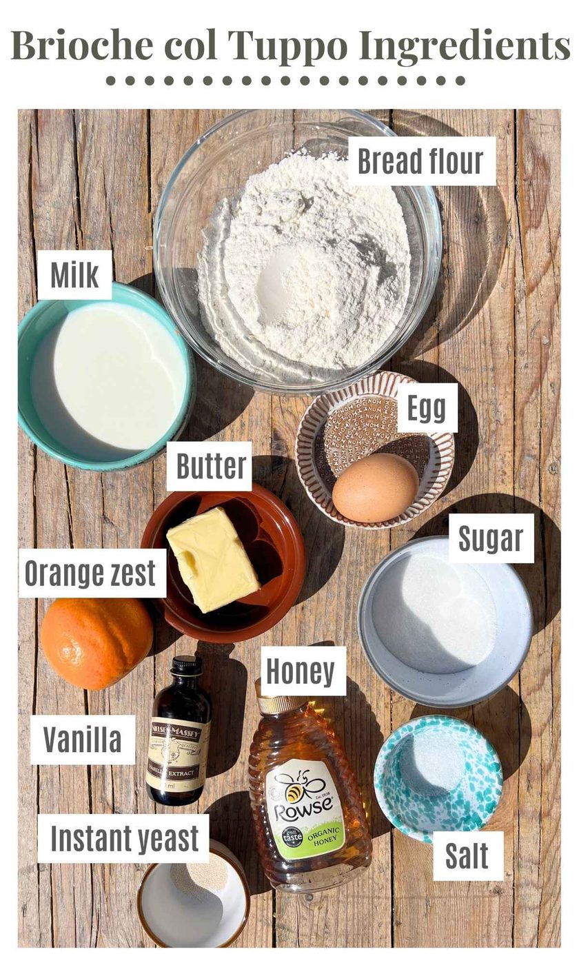 All the ingredients needed to make Sicilian brioche buns laying on a rustic wooden surface.