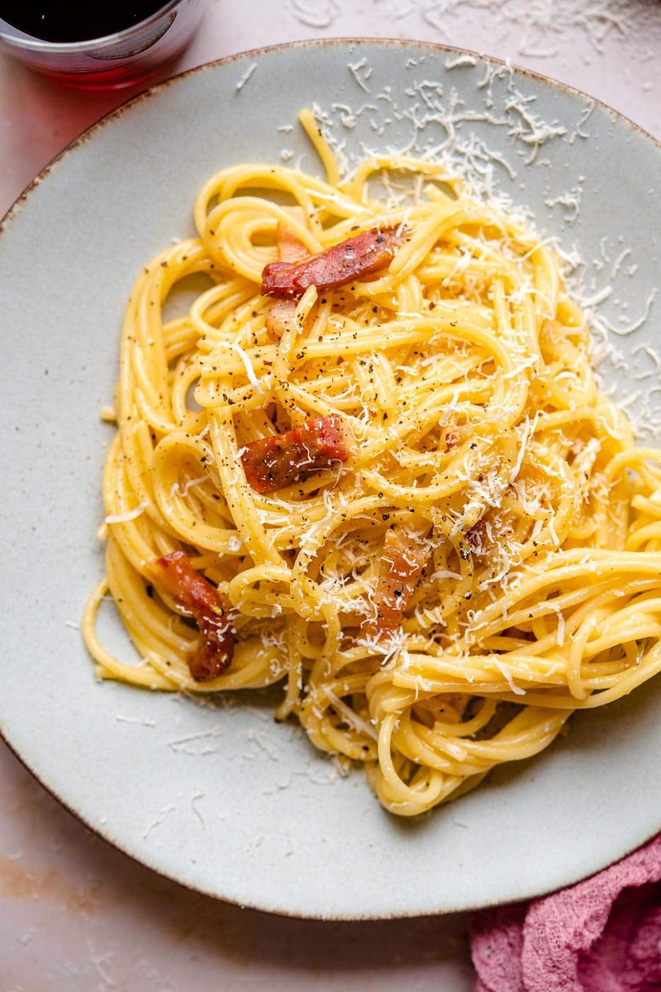 A close up of spaghetti on a plate with pieces of guanciale