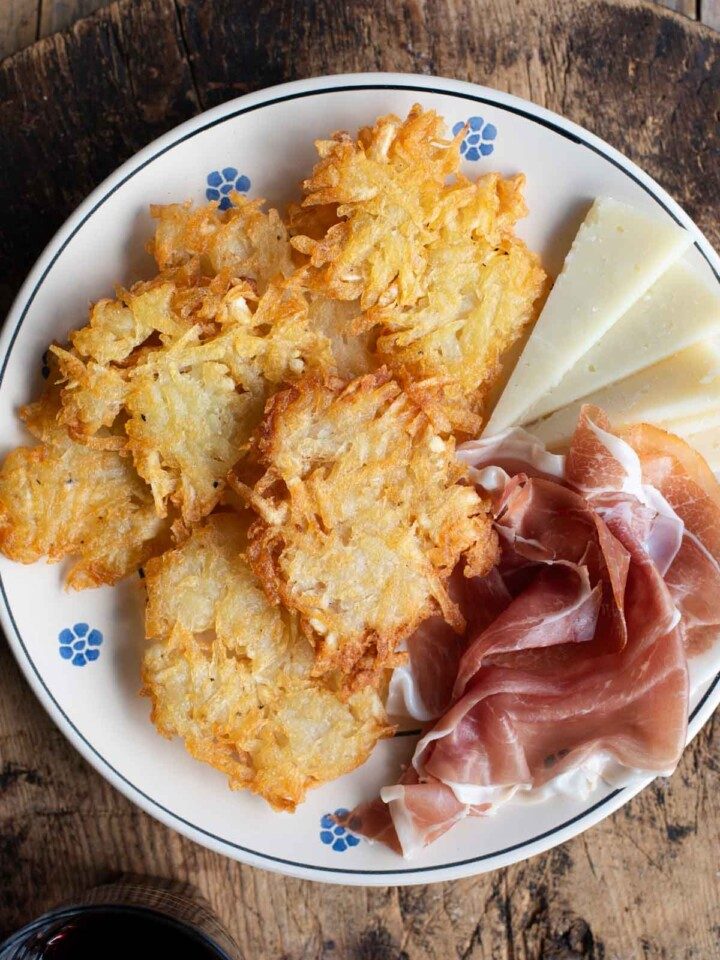 An overhead shot of Italian potato fritters on a plate with some cured meat and cheese.
