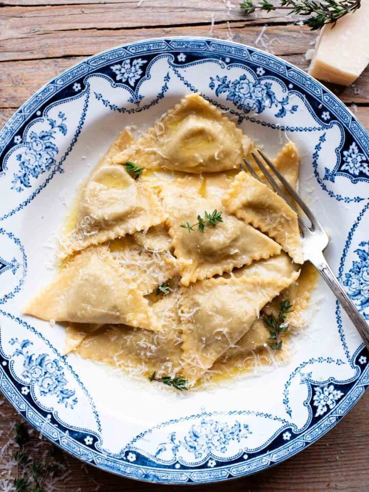 An overhead shot of taleggio and mushroom Triangoli pasta in a blue bowl with a butter sauce.