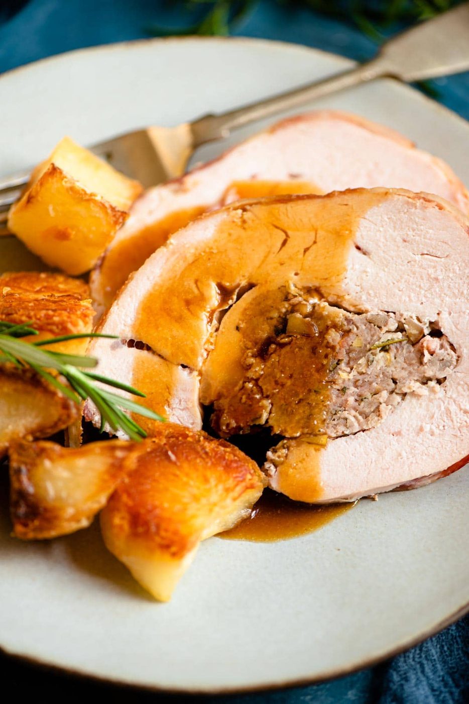 A close up of slices of stuffed turkey breast on a plate with gravy