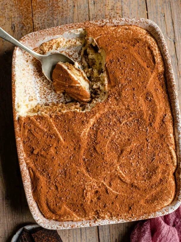 an overhead shot of a tiramisu in a dish with a slice out