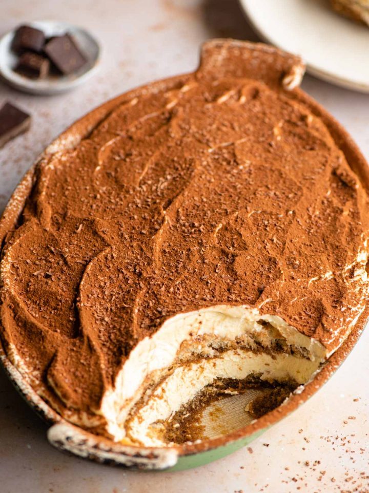 An oval dish of Tiramisu with a scoop out