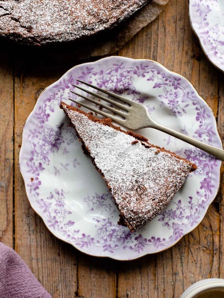 An overhead shot of a slice of chocolate torta caprese on a pink patterned plate