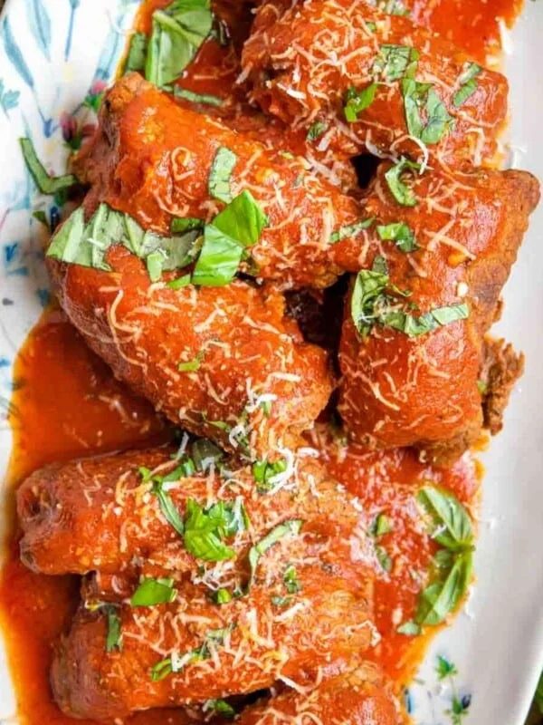 An overhead shot of beef braciole on a platter with tomato sauce
