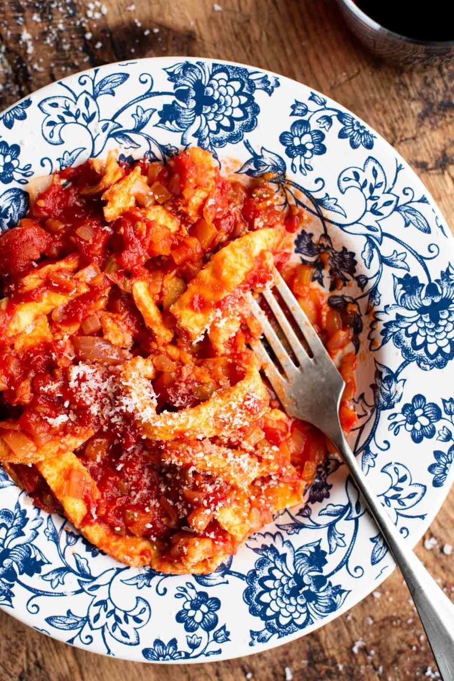A close up of a fork in a bowl of Italian Trippa Finta (omelette in tomato sauce).