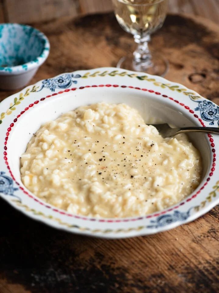 A bowl of cheesy Risotto alla valdostana sitting on a wooden board.