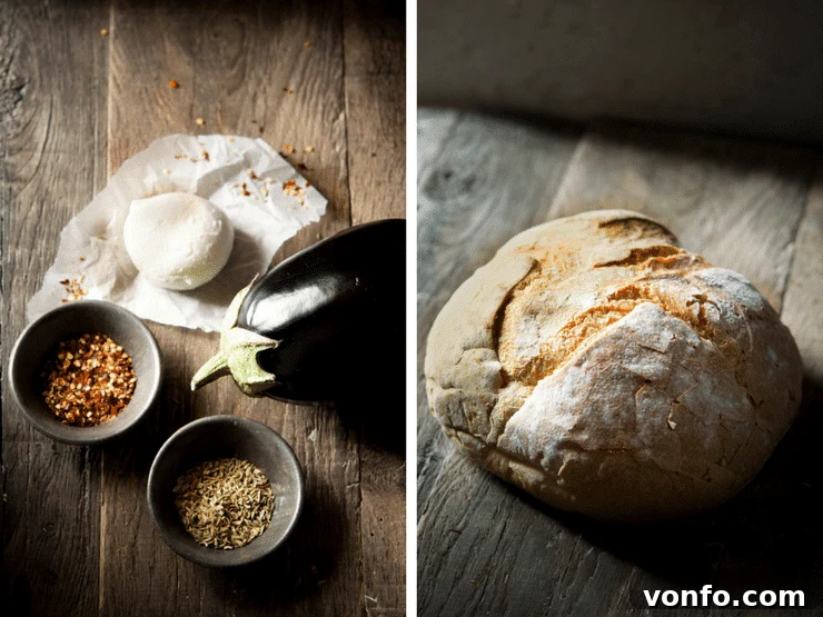 A collection of ingredients for Eggplant Bruschetta laid out on a wooden surface: sliced eggplant, fresh mozzarella, red pepper flakes, fennel seeds, and a loaf of crusty Italian bread.