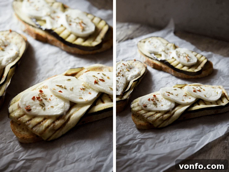 A close-up view of assembled eggplant bruschetta with grilled eggplant and fresh mozzarella on crusty bread, awaiting the final melt.