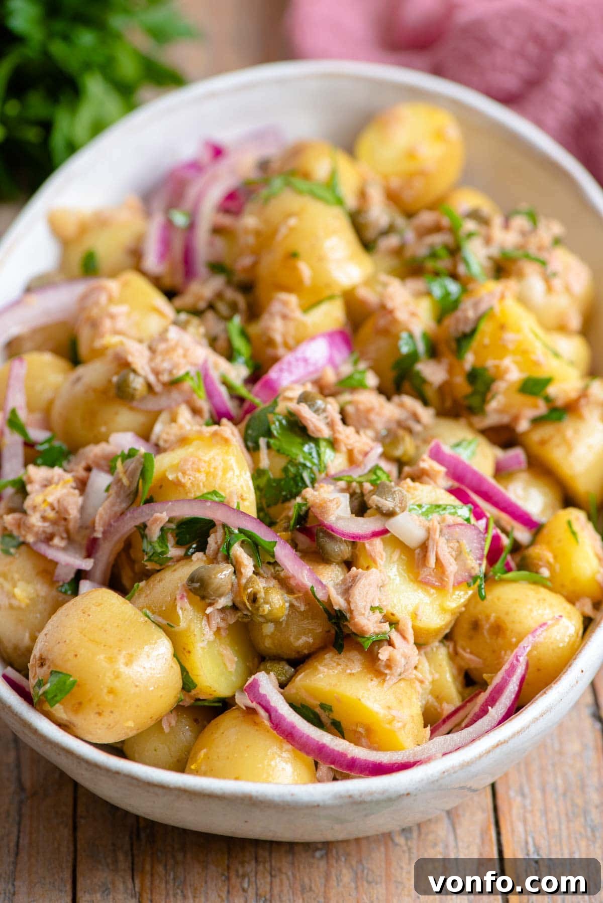 Vibrant Italian Tuna Potato Salad 5 A close-up shot of the finished Italian tuna potato salad in a serving bowl, showcasing the red onion, capers, and fresh parsley.