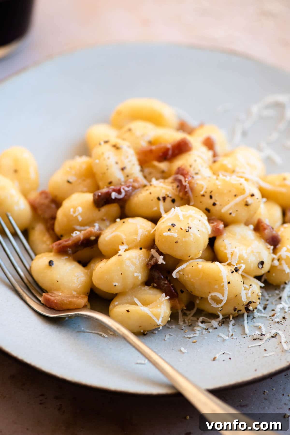 Pillowy Gnocchi Carbonara 6 A close-up shot of creamy gnocchi carbonara on a plate, garnished with fresh black pepper