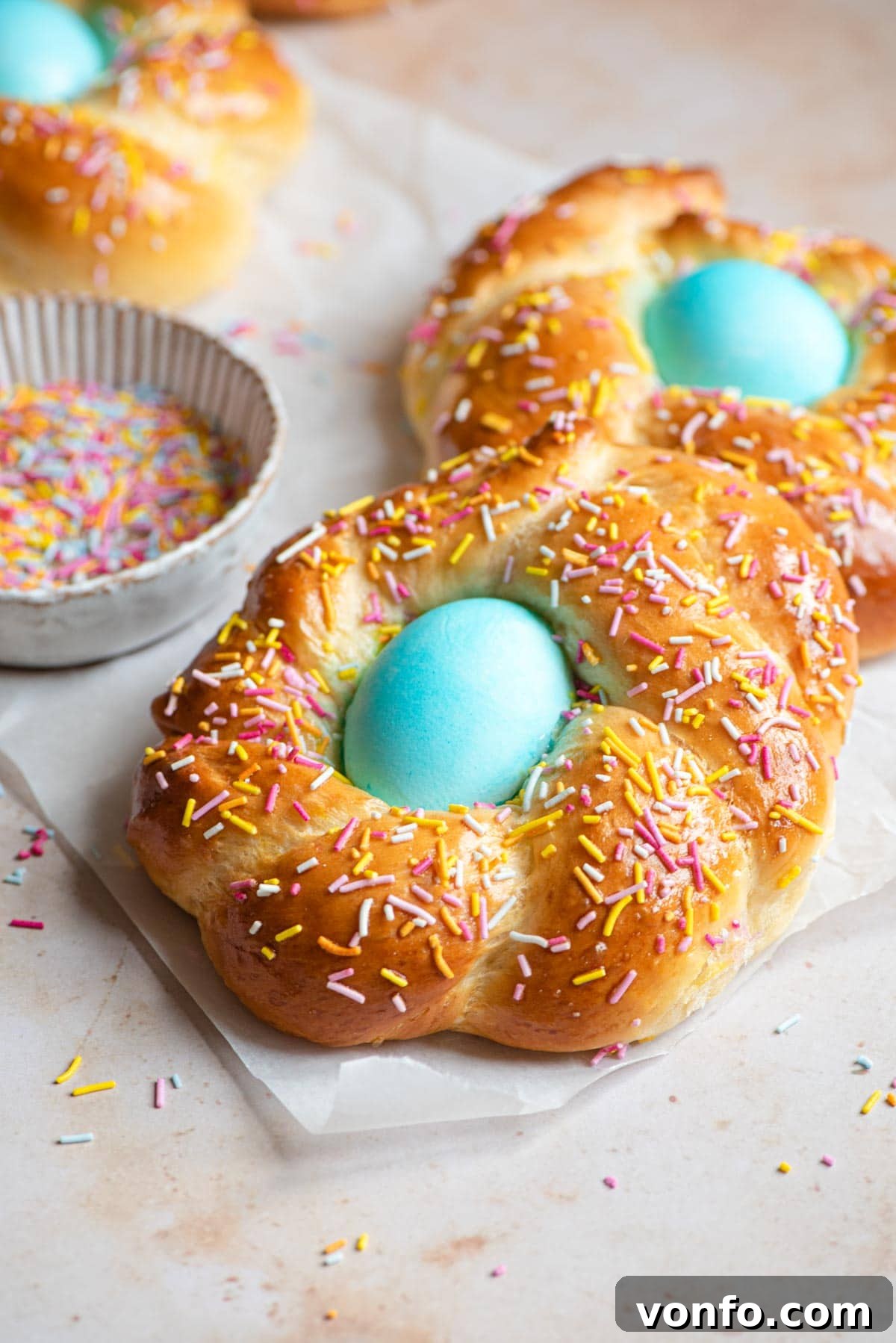 Italian Easter bread with a blue egg in the middle covered with sprinkles, showcasing a beautifully braided, golden-brown loaf.