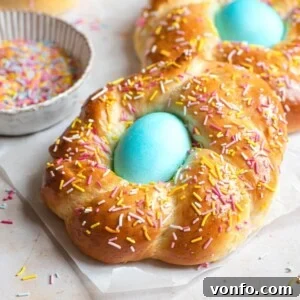 A close up of Italian Easter bread with sprinkles and a blue egg in the middle, displaying its irresistible texture and festive decoration.