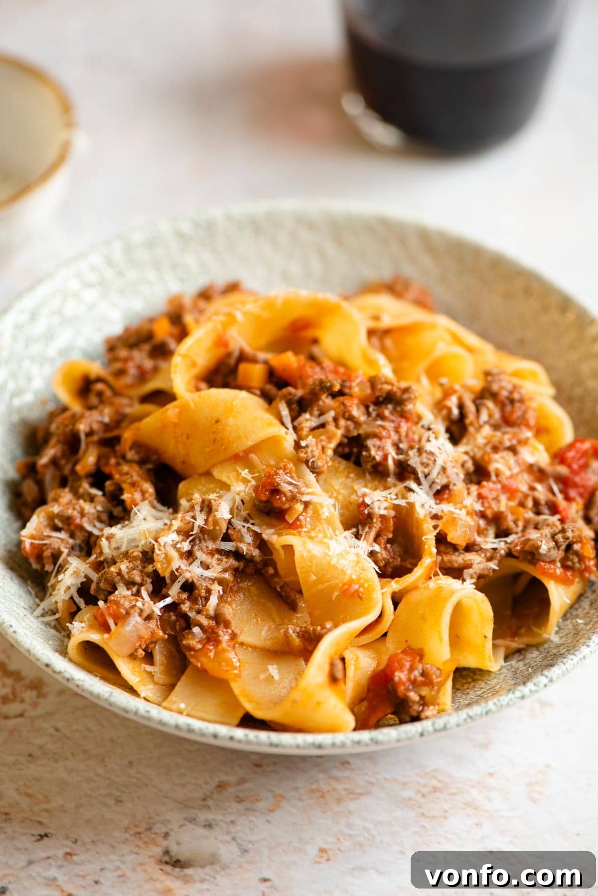 Slow-Simmered Italian Lamb Ragu 2 A bowl of Italian Lamb Ragu with pappardelle pasta, garnished with fresh rosemary and grated Pecorino cheese.
