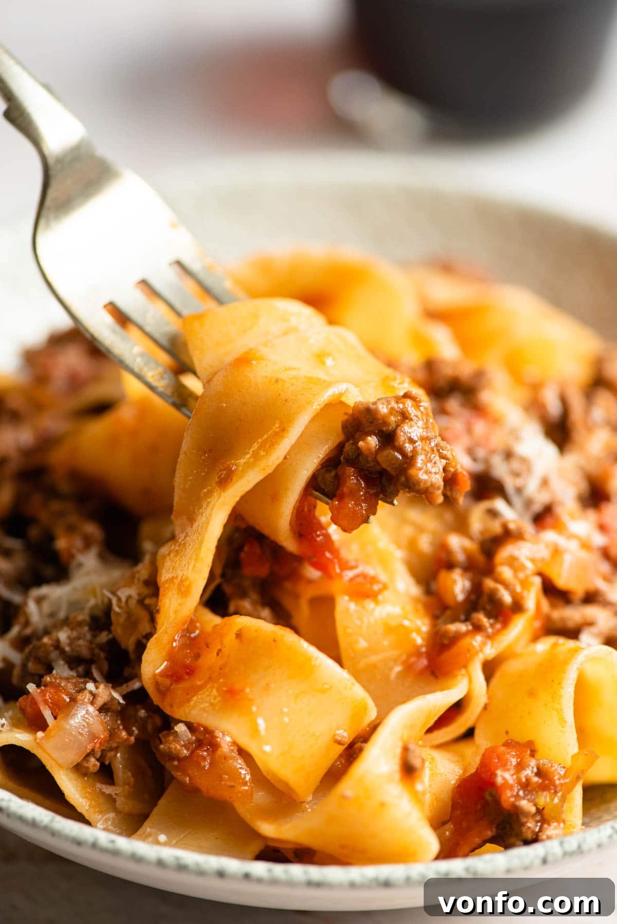 Slow-Simmered Italian Lamb Ragu 6 A close-up view of succulent Italian lamb ragu intimately coating strands of pappardelle pasta on a fork, ready to be enjoyed.