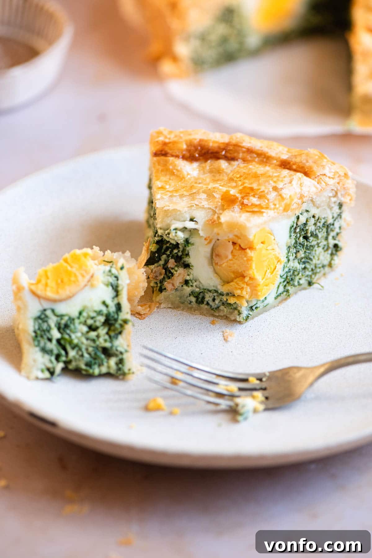 A slice of Torta Pasqualina on a plate cut in half, showcasing the cross-section