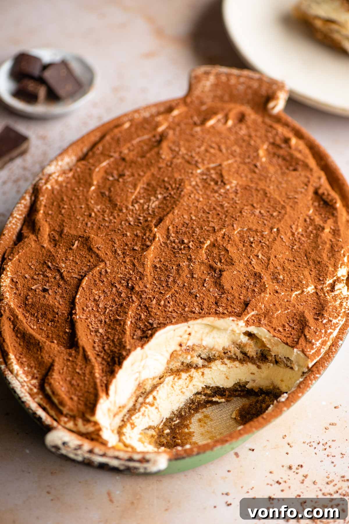 Velvet Cloud Tiramisu 2 An oval dish of Eggless Tiramisu with a scoop removed, revealing the layers of coffee-soaked ladyfingers and creamy mascarpone