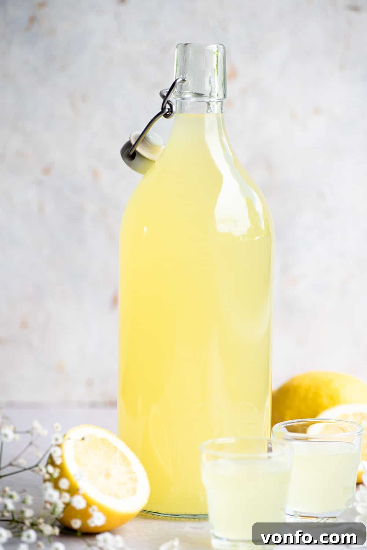 A bottle of homemade Limoncello with two shots glasses beside it